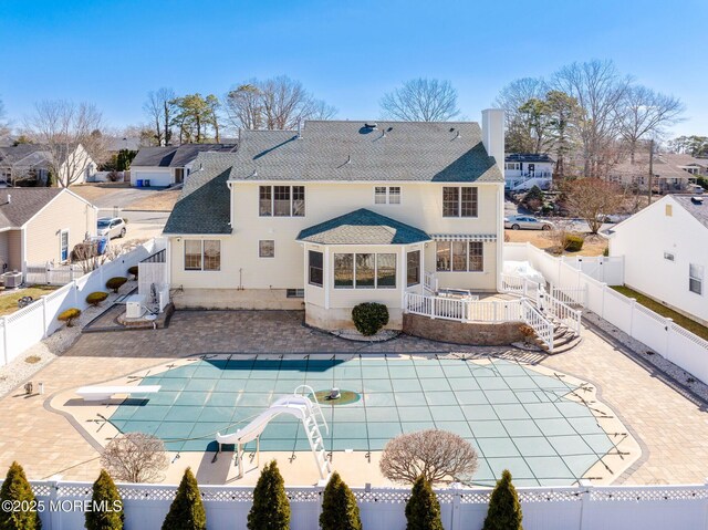 back of property featuring a fenced backyard, a fenced in pool, and a patio