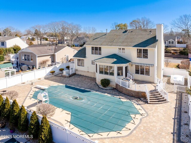 back of house with a patio area, a fenced backyard, a chimney, and a fenced in pool