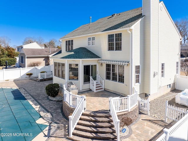 back of house with a fenced backyard, a shingled roof, a fenced in pool, and a patio