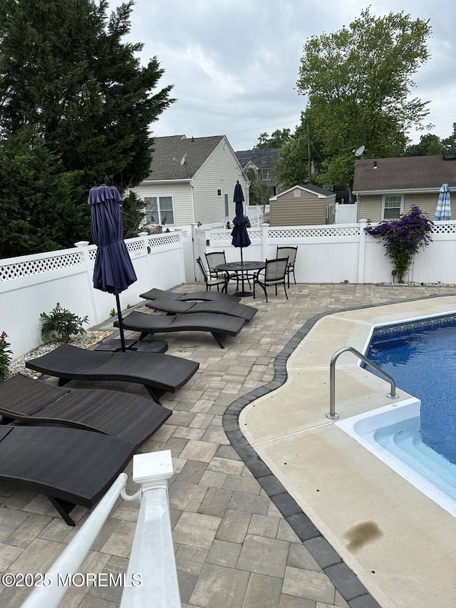 view of pool featuring a fenced in pool, outdoor dining space, a fenced backyard, and a patio