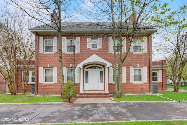 view of front of home featuring a front yard, a chimney, and brick siding