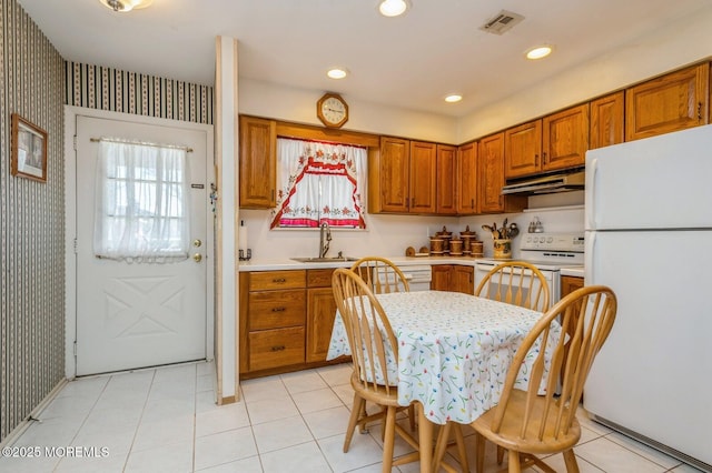 kitchen with visible vents, wallpapered walls, under cabinet range hood, white appliances, and a sink