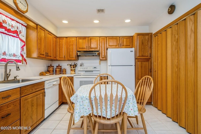 kitchen featuring a sink, white appliances, under cabinet range hood, and brown cabinets