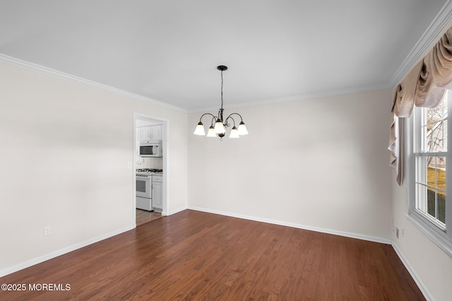 spare room with a notable chandelier, dark wood-type flooring, baseboards, and ornamental molding