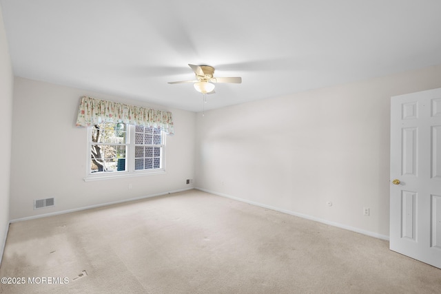 carpeted empty room with visible vents, baseboards, and a ceiling fan