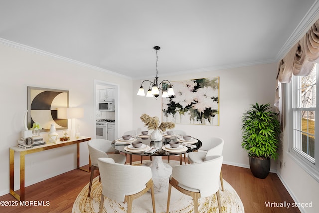 dining room with a notable chandelier, ornamental molding, baseboards, and wood finished floors