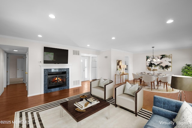 living area with visible vents, wood finished floors, a high end fireplace, and ornamental molding