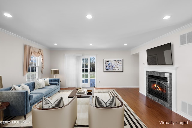 living area featuring a wealth of natural light, visible vents, and a glass covered fireplace