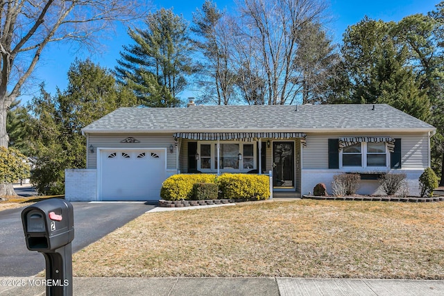 ranch-style house with a garage, brick siding, a front yard, and aphalt driveway