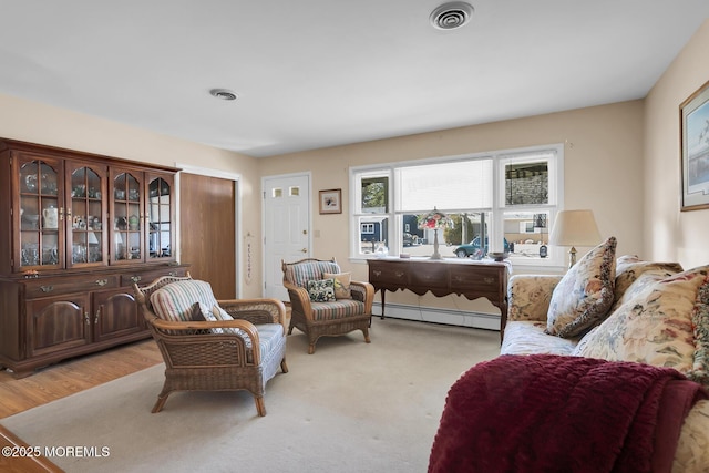 living area featuring light wood finished floors, a baseboard radiator, and visible vents