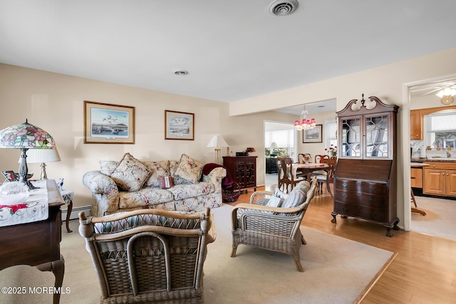 living room with light wood finished floors, a baseboard radiator, and visible vents