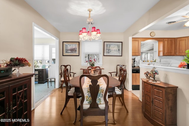 dining room with wood finished floors, visible vents, and an inviting chandelier