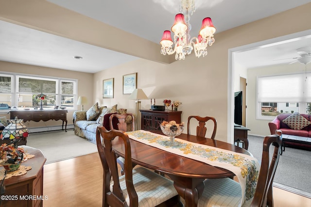 dining area featuring a wealth of natural light, wood finished floors, baseboard heating, and ceiling fan with notable chandelier