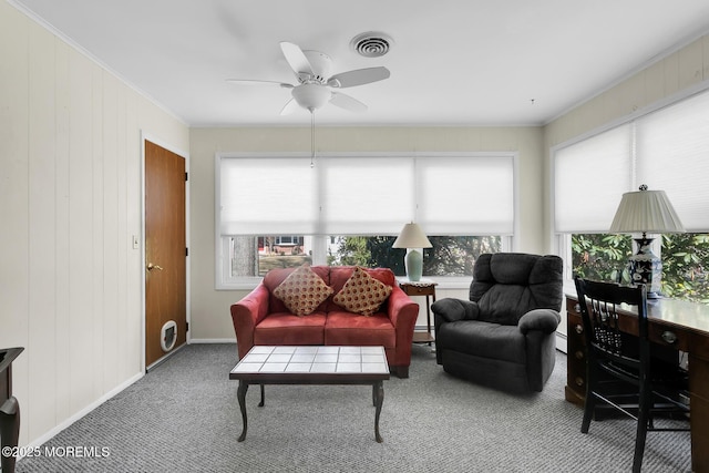 carpeted living room with ceiling fan, a baseboard heating unit, visible vents, baseboards, and crown molding