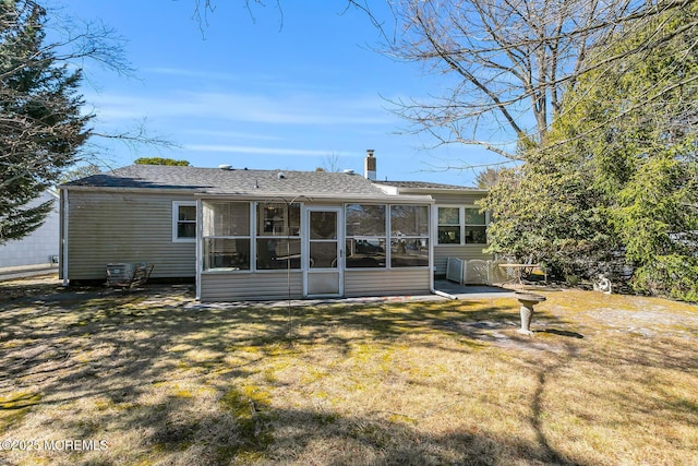 rear view of property with a sunroom, a yard, and a chimney