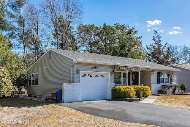 ranch-style house featuring an attached garage, roof with shingles, aphalt driveway, and brick siding