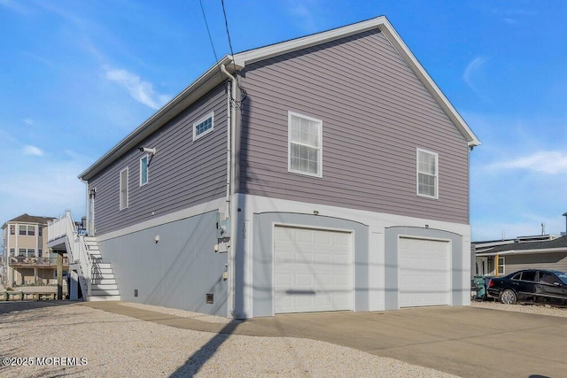 view of side of property with an attached garage, stairway, and concrete driveway