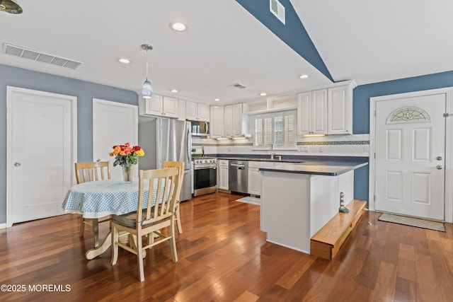 kitchen with dark wood-style floors, appliances with stainless steel finishes, backsplash, and visible vents