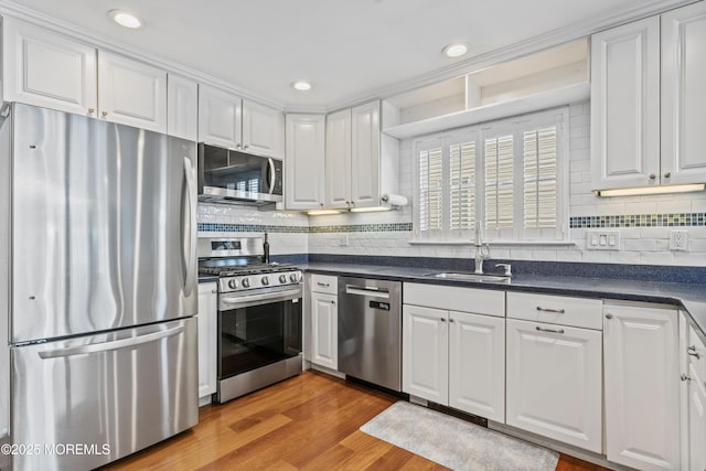 kitchen featuring dark countertops, white cabinetry, stainless steel appliances, and a sink