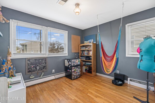 miscellaneous room with a baseboard heating unit, visible vents, baseboards, and wood finished floors