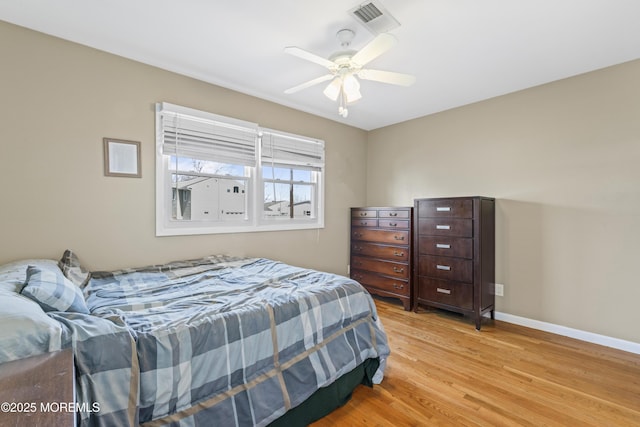 bedroom with light wood-style floors, baseboards, visible vents, and ceiling fan