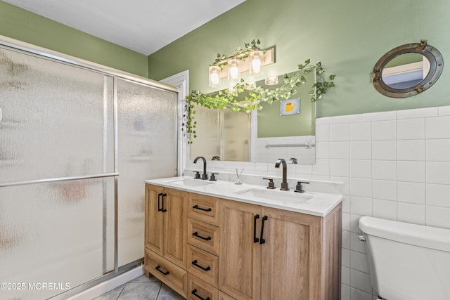 bathroom with a stall shower, a sink, toilet, and tile patterned floors