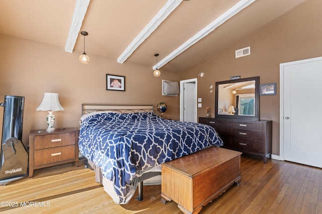 bedroom featuring visible vents, vaulted ceiling with beams, and wood finished floors