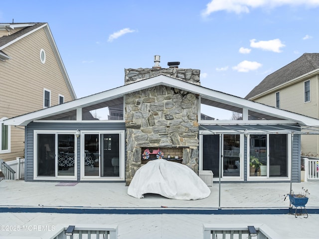 back of house with stone siding, a fireplace, and a patio