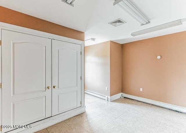 empty room featuring visible vents, baseboards, a baseboard heating unit, and light tile patterned flooring