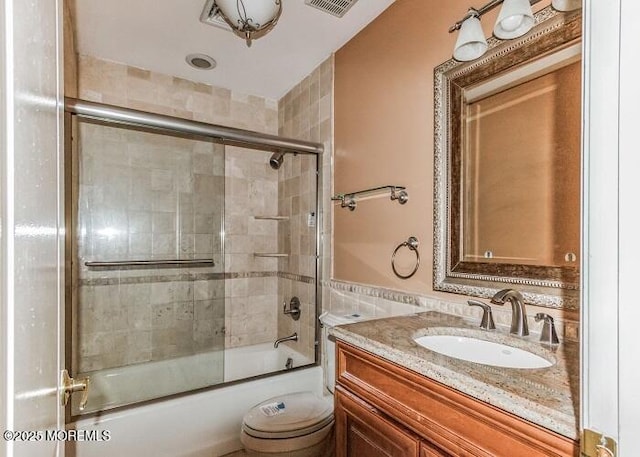 full bathroom featuring visible vents, bath / shower combo with glass door, vanity, and toilet