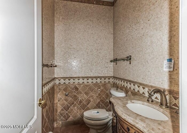 half bathroom featuring toilet, tile walls, and vanity