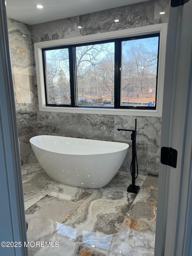 full bathroom featuring marble finish floor and a freestanding bath