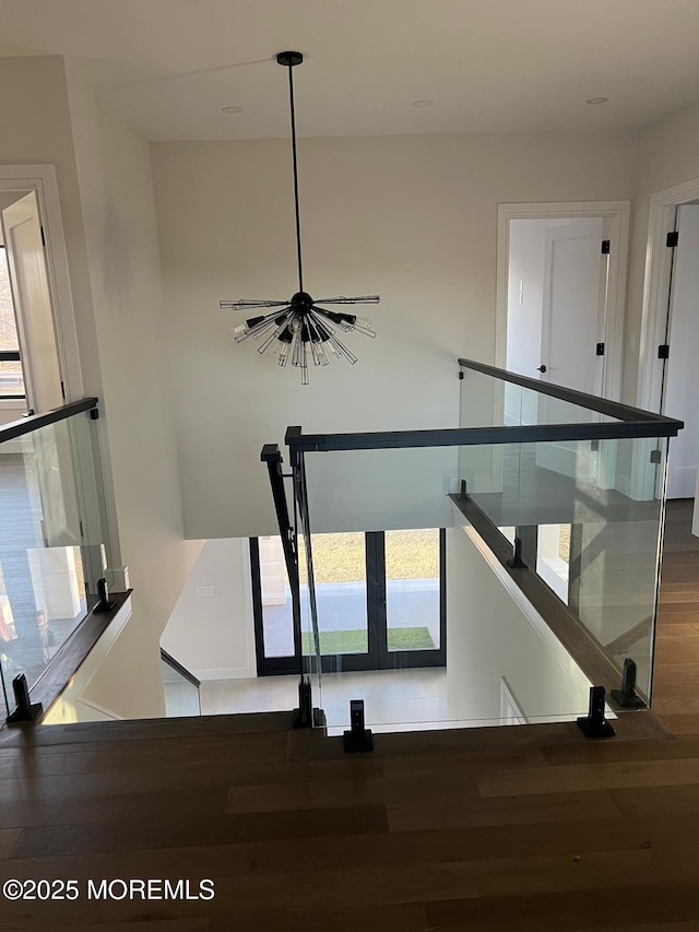 stairway featuring a chandelier and wood finished floors