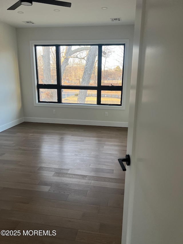 spare room featuring a ceiling fan, dark wood-style flooring, and baseboards