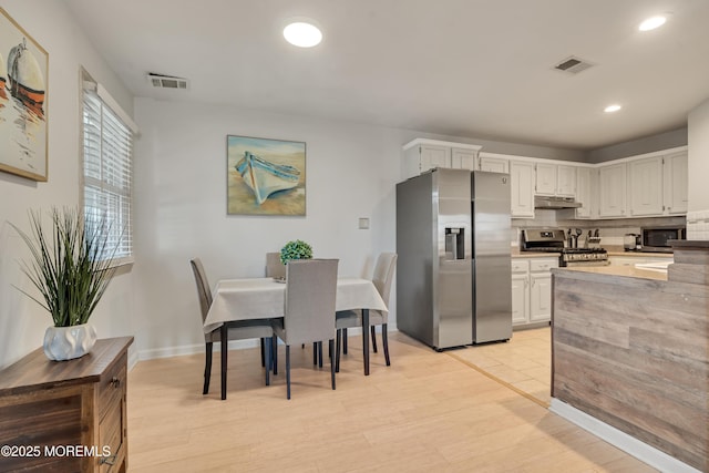 kitchen with under cabinet range hood, visible vents, appliances with stainless steel finishes, and backsplash