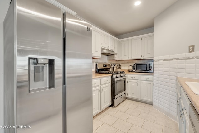 kitchen with light tile patterned floors, under cabinet range hood, stainless steel appliances, white cabinets, and light countertops