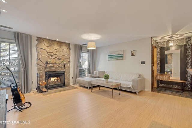 living area featuring a stone fireplace, wood finished floors, visible vents, and recessed lighting