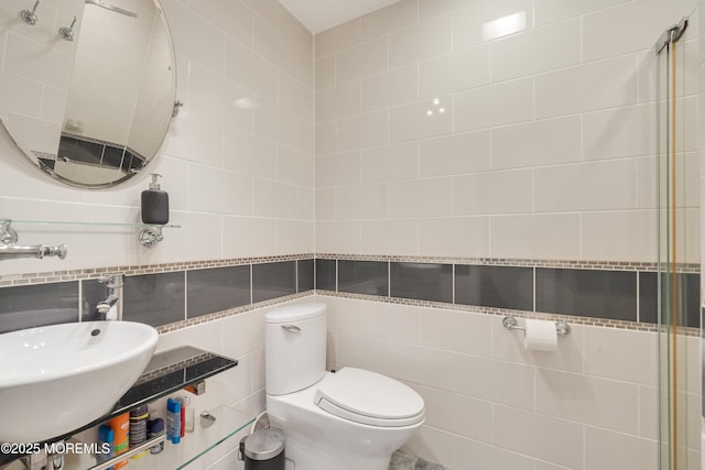 bathroom featuring a sink, tile walls, and toilet