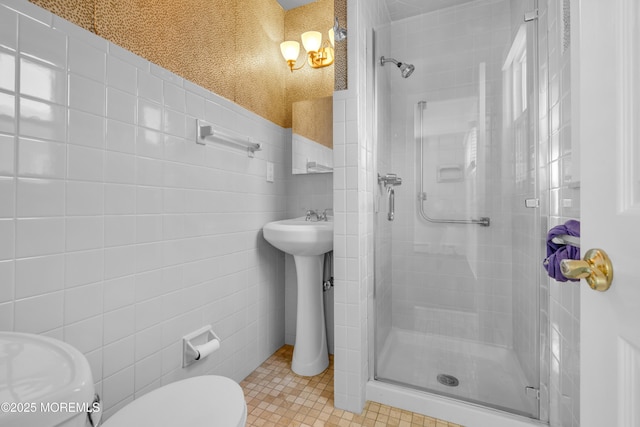 bathroom with a sink, toilet, tile walls, and a shower stall