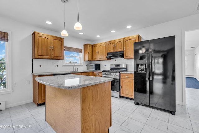 kitchen with under cabinet range hood, stainless steel appliances, a sink, light stone countertops, and tasteful backsplash