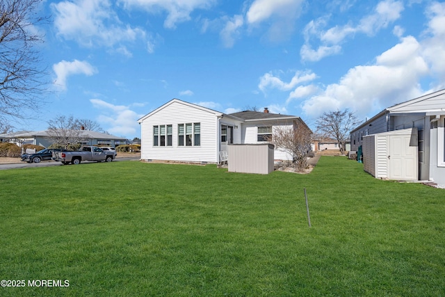 rear view of house featuring a storage shed, crawl space, an outdoor structure, and a lawn