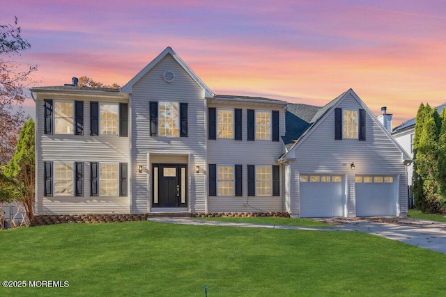 colonial-style house with a garage, driveway, and a front lawn