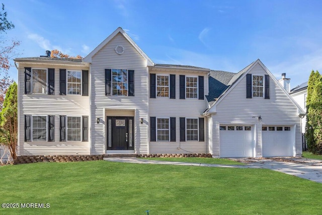 colonial inspired home with driveway, a chimney, and a front yard