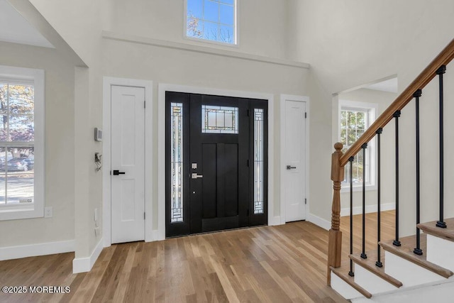 foyer entrance featuring baseboards, stairway, and wood finished floors