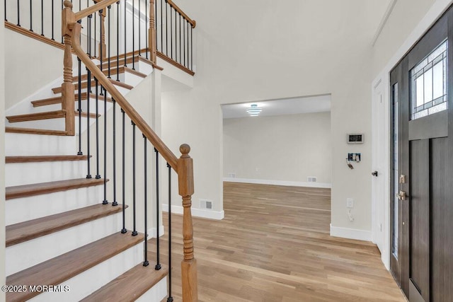 entrance foyer with stairs, visible vents, baseboards, and wood finished floors