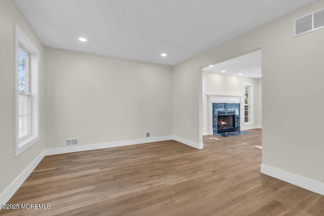 unfurnished living room with plenty of natural light, visible vents, and wood finished floors