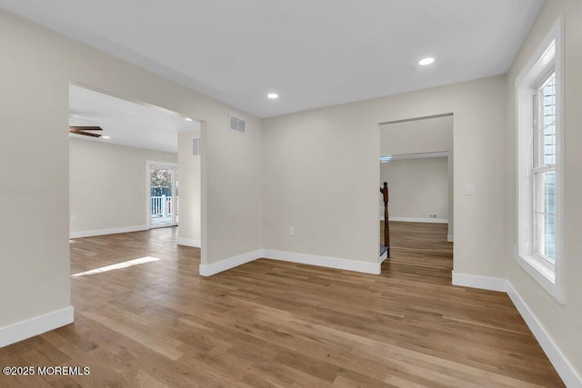 spare room with light wood-type flooring, visible vents, and baseboards