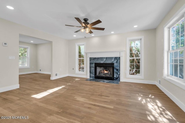 unfurnished living room featuring recessed lighting, a fireplace, baseboards, and wood finished floors