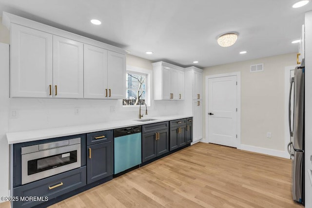 kitchen with visible vents, light wood-style flooring, stainless steel appliances, white cabinetry, and a sink