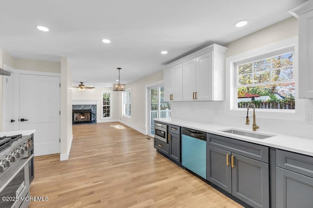 kitchen featuring light countertops, appliances with stainless steel finishes, a high end fireplace, white cabinetry, and a sink